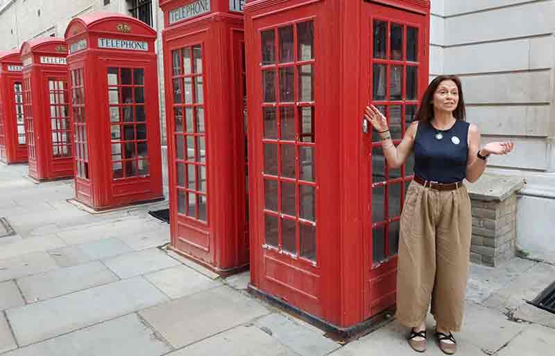 Standing by 5 red telephone boxes.